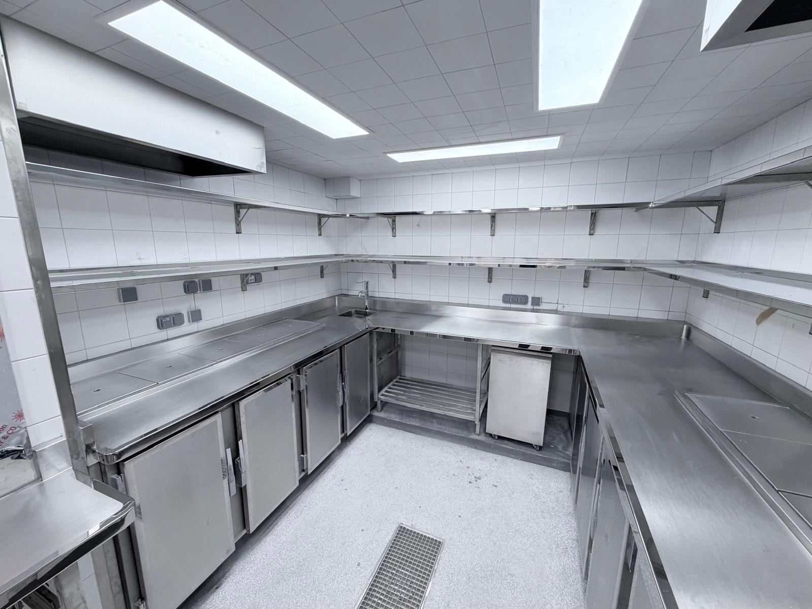 Plan de travail inox en angle avec rangements intégrés et étagères murales conçu par l'atelier de fabrication inox Paris Inox