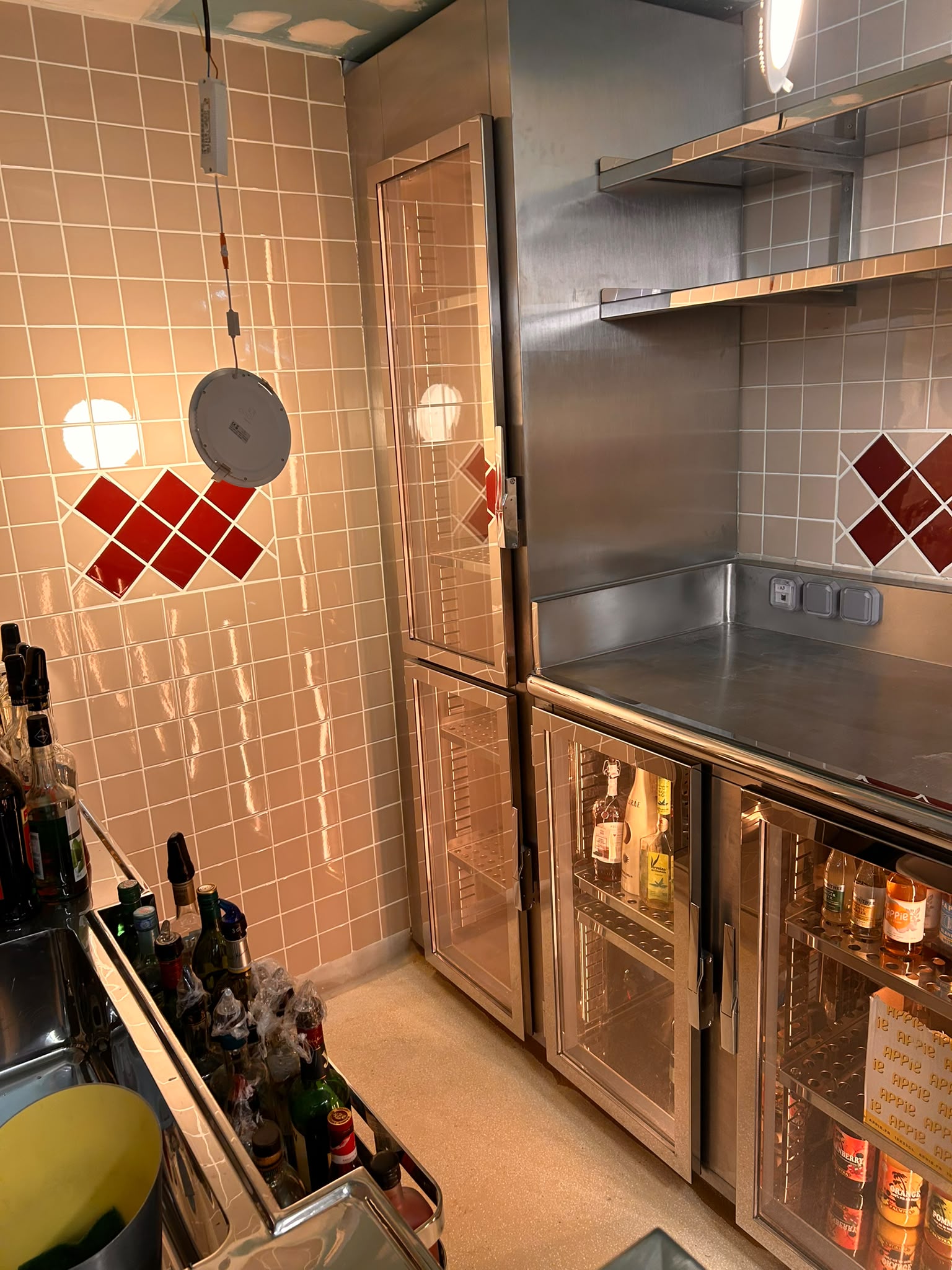Arrière-bar inox avec vitrines réfrigérées Aménagement arrière-bar en inox comprenant vitrines réfrigérées, plan de travail et rangements réalisés sur mesure.