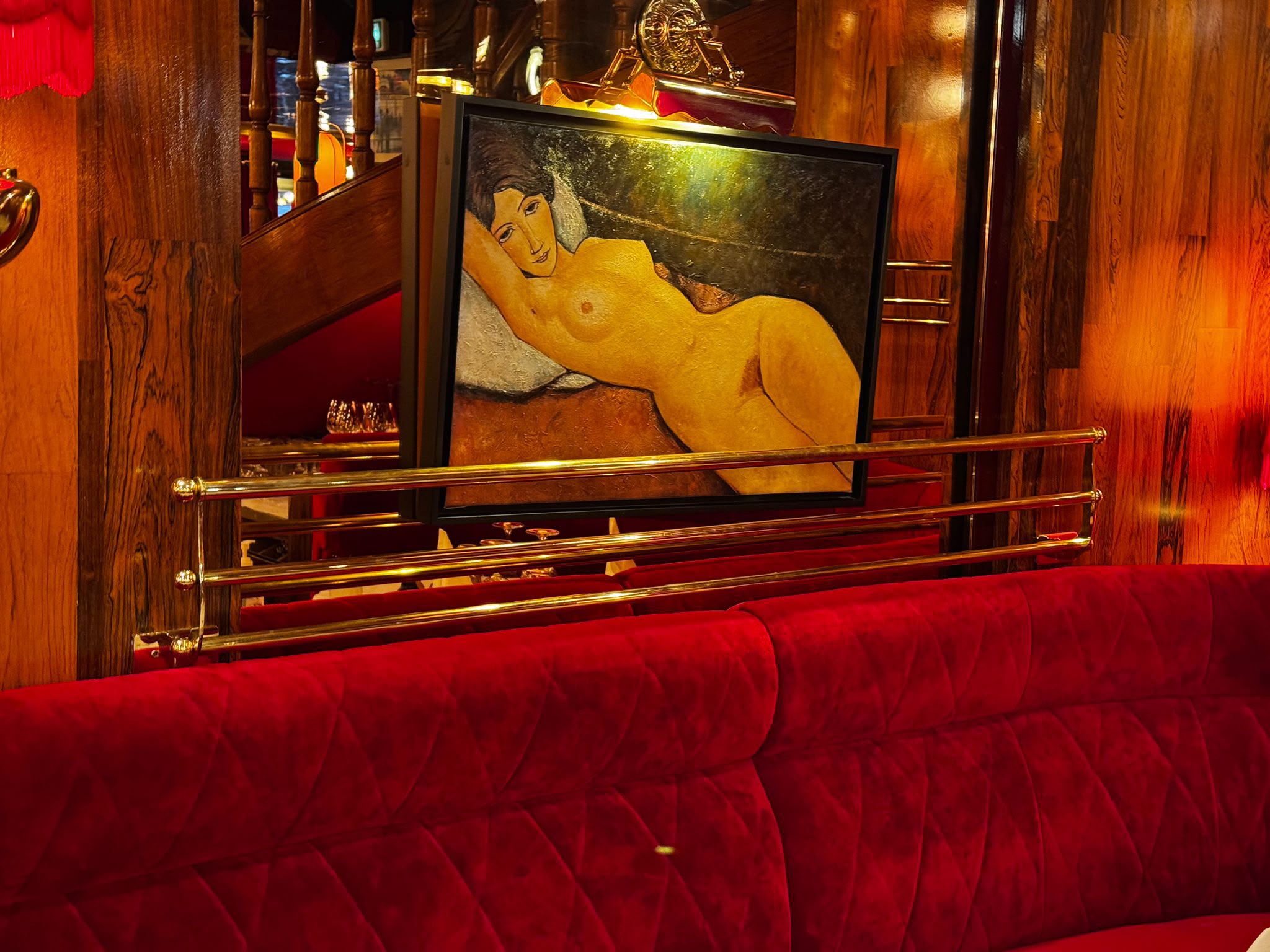 Chapelière en laiton pour brasserie, réalisée par Paris Inox, au-dessus d'une banquette en velours rouge