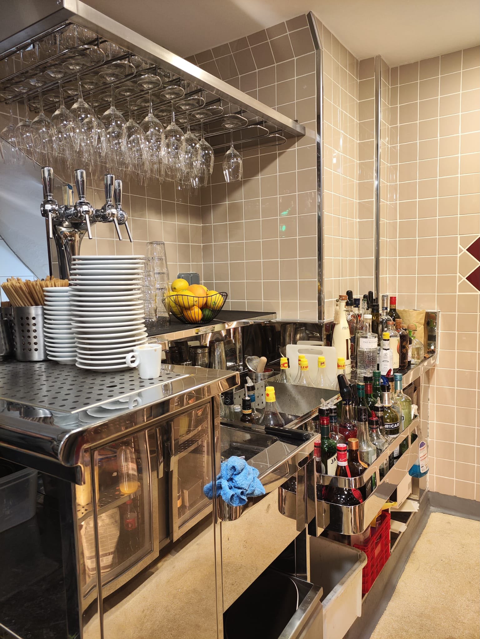 Comptoir de bar inox avec porte-verres Comptoir de bar en inox poli avec porte-verres suspendu, rangements intégrés et aménagement sur mesure.