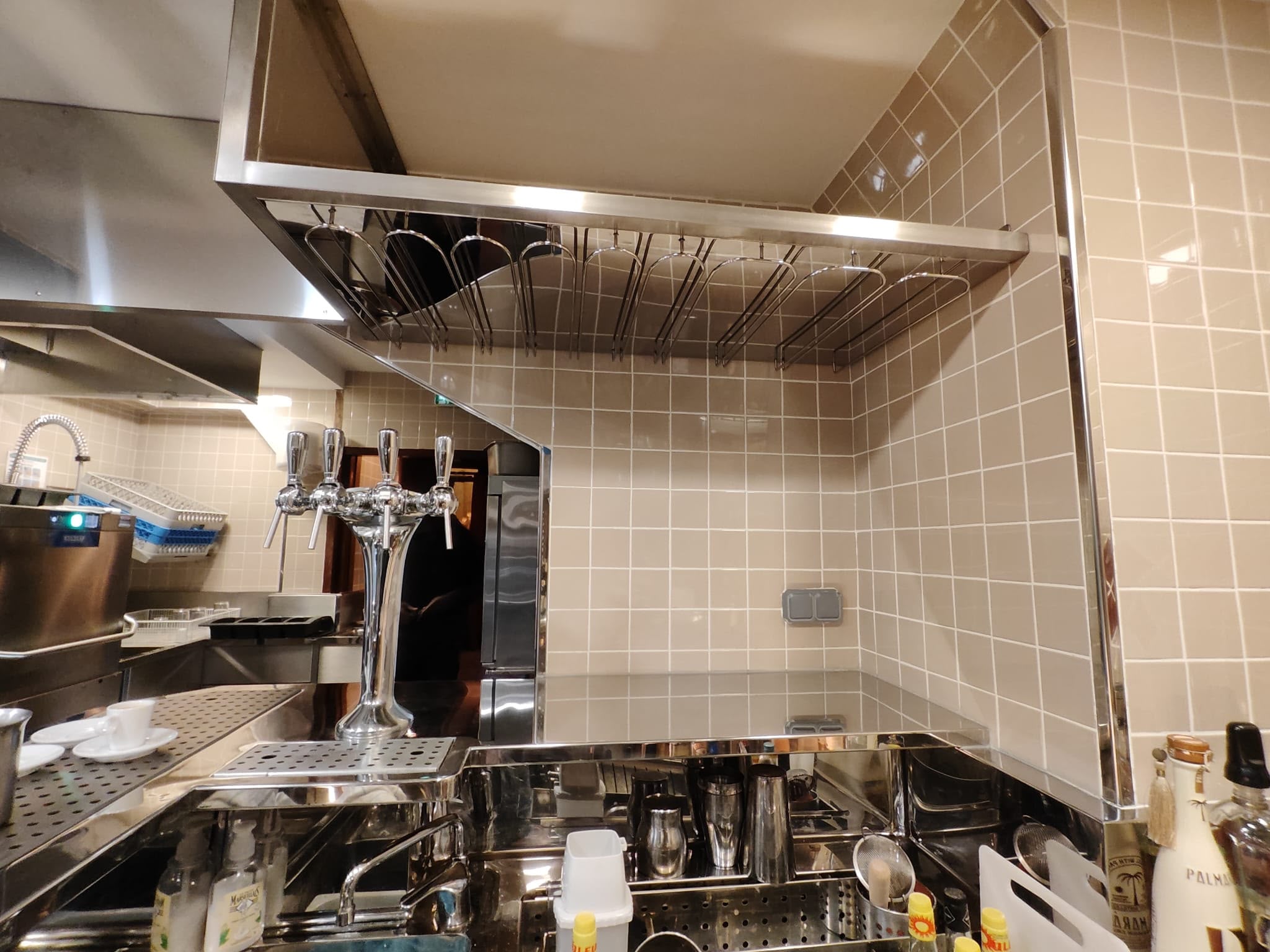 Étagère suspendue inox porte-verres Étagère suspendue en inox avec supports porte-verres intégrés réalisée sur mesure pour un espace bar.