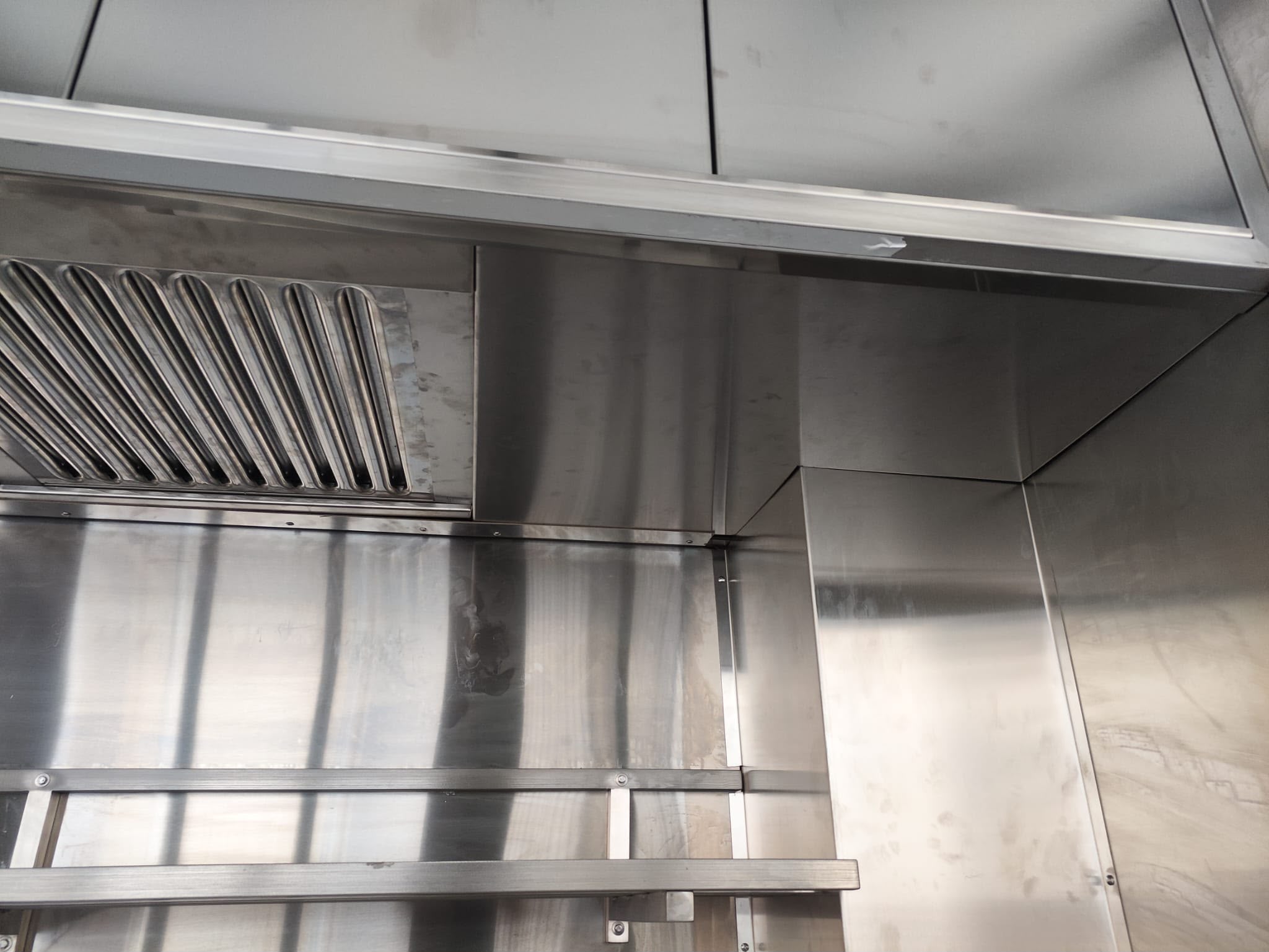Hotte professionnelle en inox sur mesure Hotte d'extraction professionnelle en inox avec filtres labyrinthes et habillage mural inox réalisée sur mesure pour cuisine professionnelle.