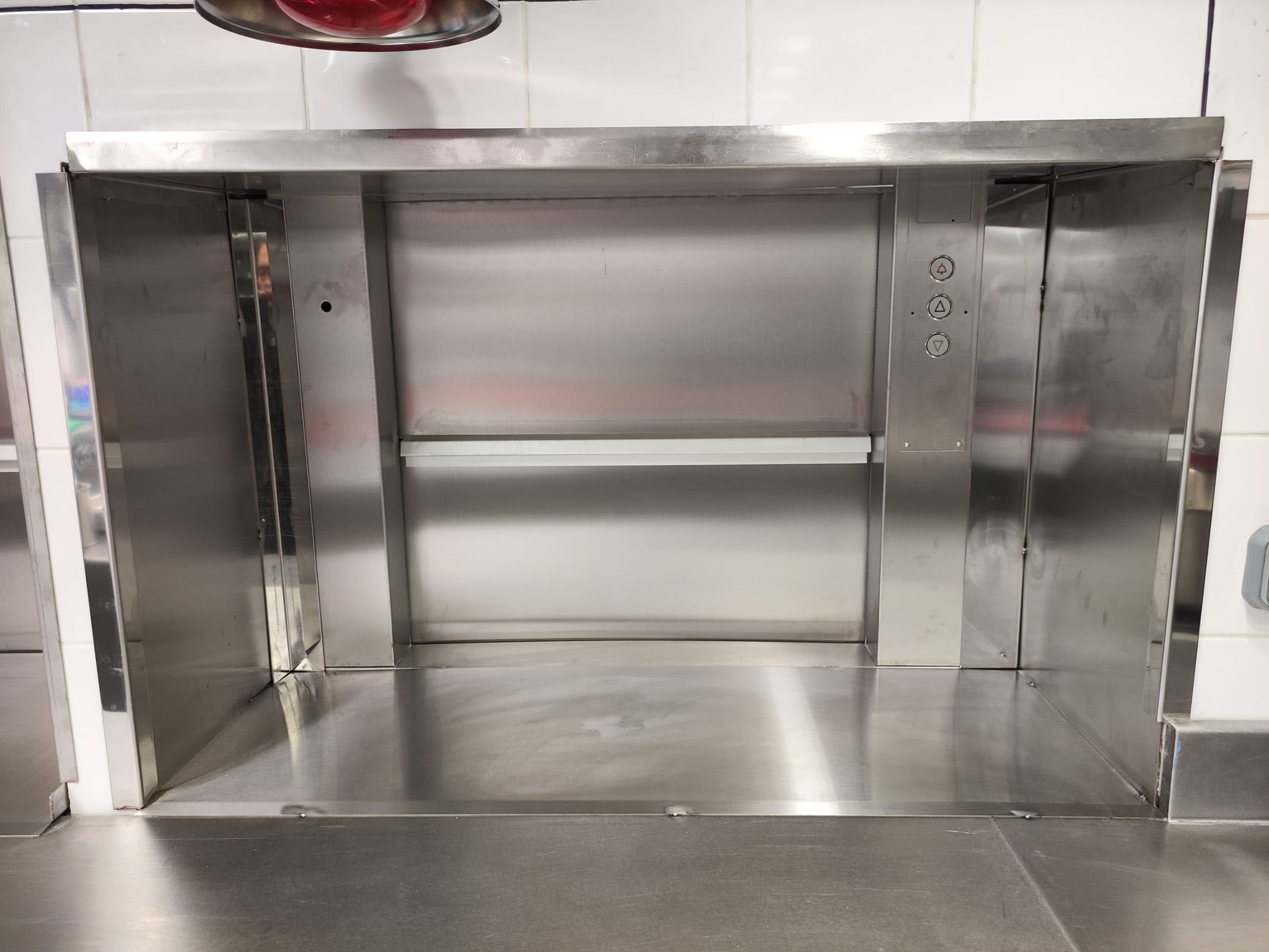 Passe-plat inox avec monte-charge intégré Monte-charge de service en inox intégré dans un plan de travail professionnel pour la liaison entre différents niveaux d’un établissement.