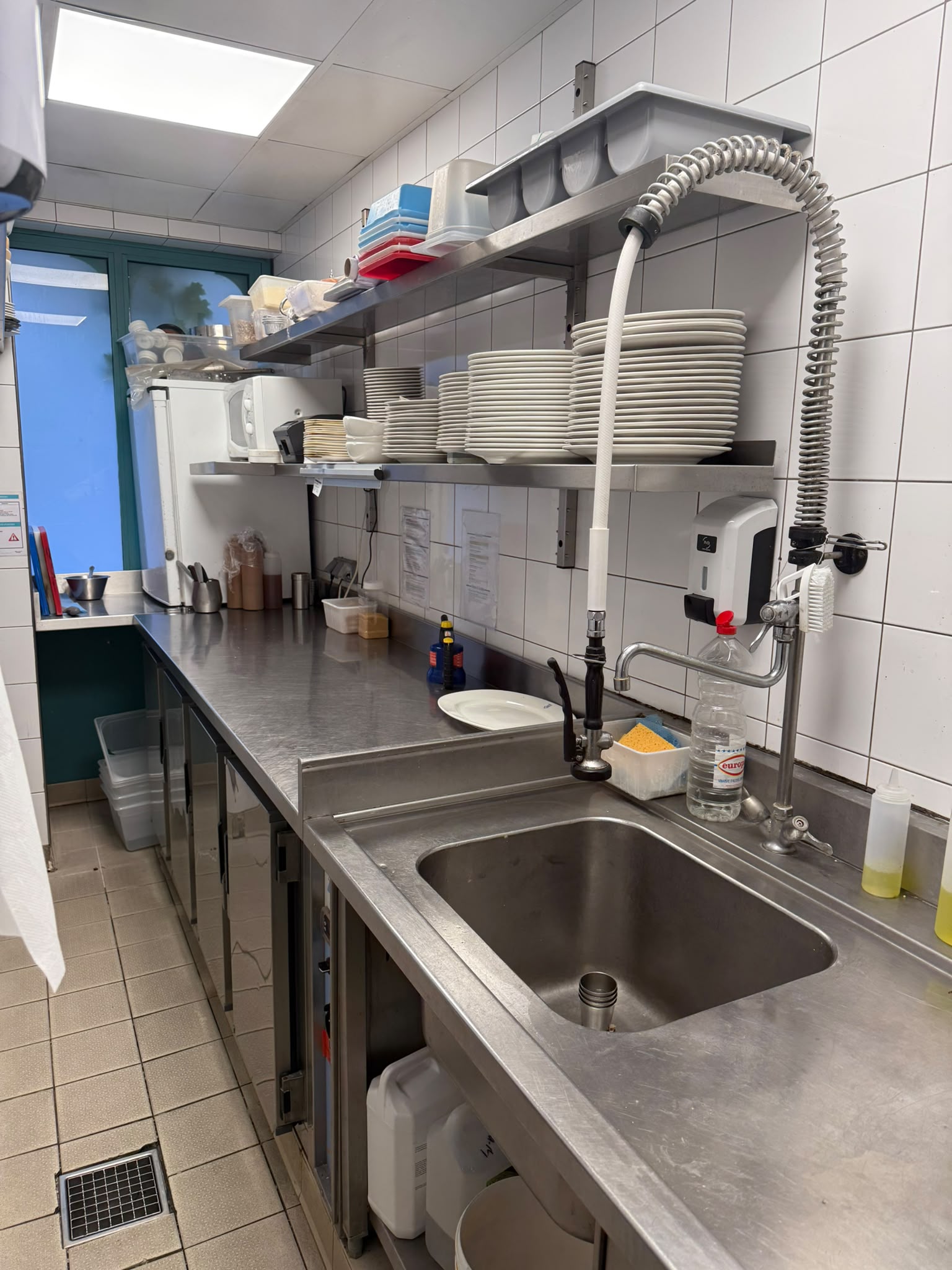 Plan de travail inox avec étagères murales Plan de travail en inox sur mesure avec étagères murales de rangement et évier intégré pour cuisine professionnelle.