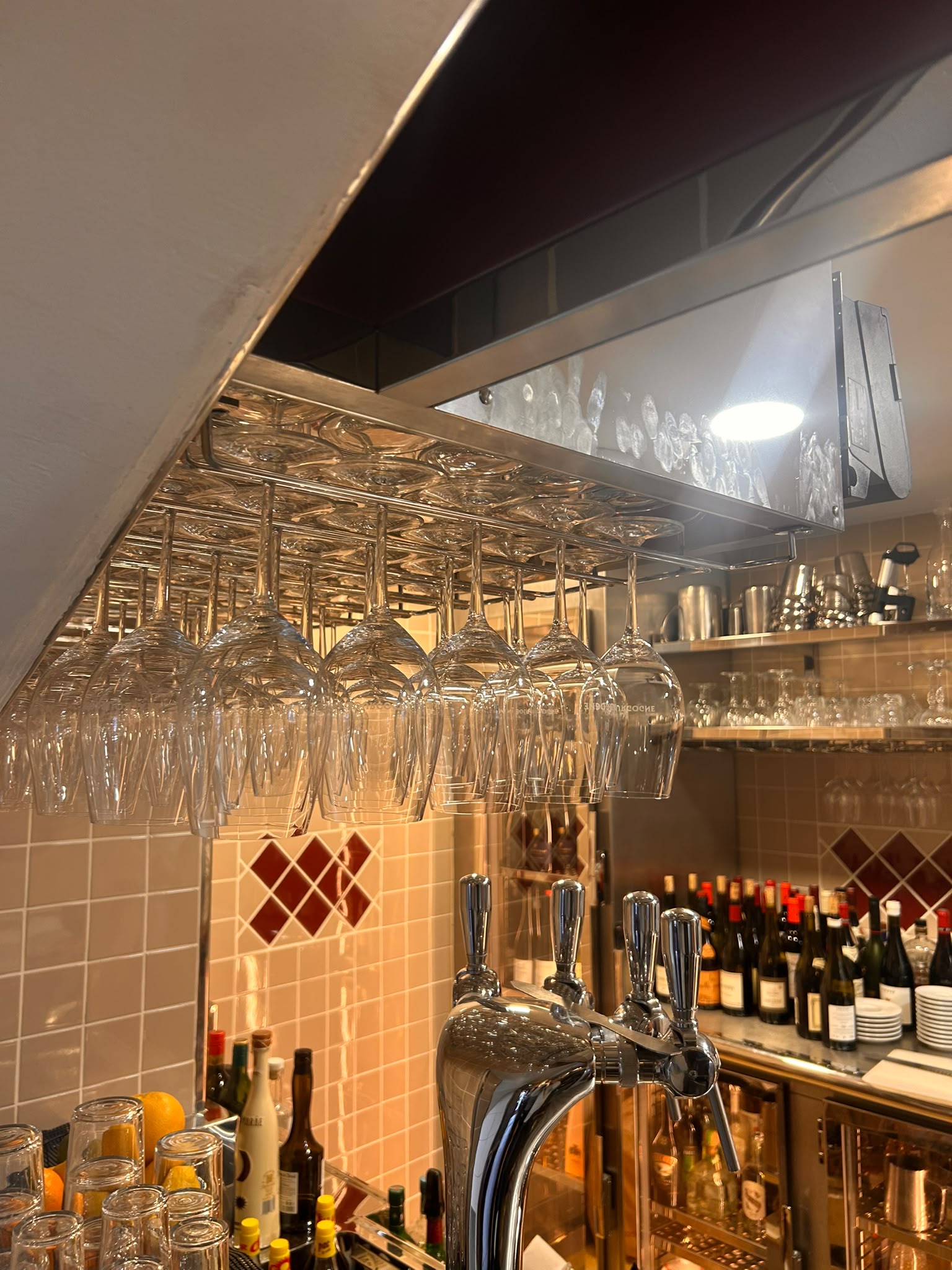 Porte-verres suspendu en inox Porte-verres suspendu en inox poli fabriqué sur mesure au-dessus d'un comptoir de bar professionnel.